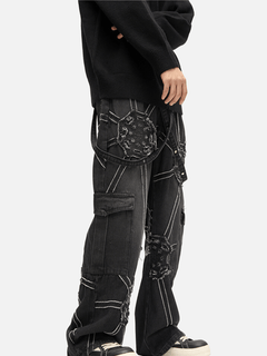 Person wearing black cargo pants with unique designs on a white background