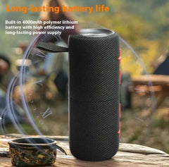 Black portable speaker with text about long-lasting battery life on a natural background